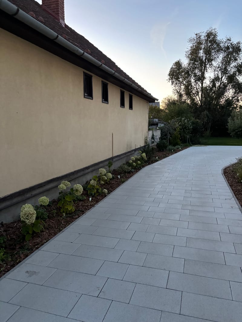 Térburkolatos út a ház mellett, fehér hortenziákkal szegélyezve